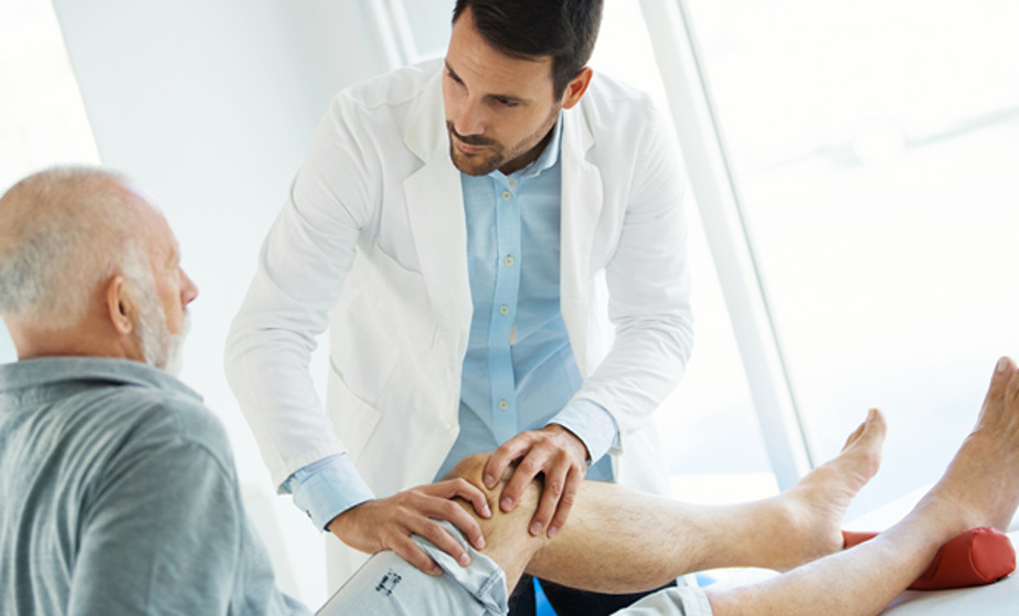 Male physician examining male patients knee 2 | MONKIKASHOP